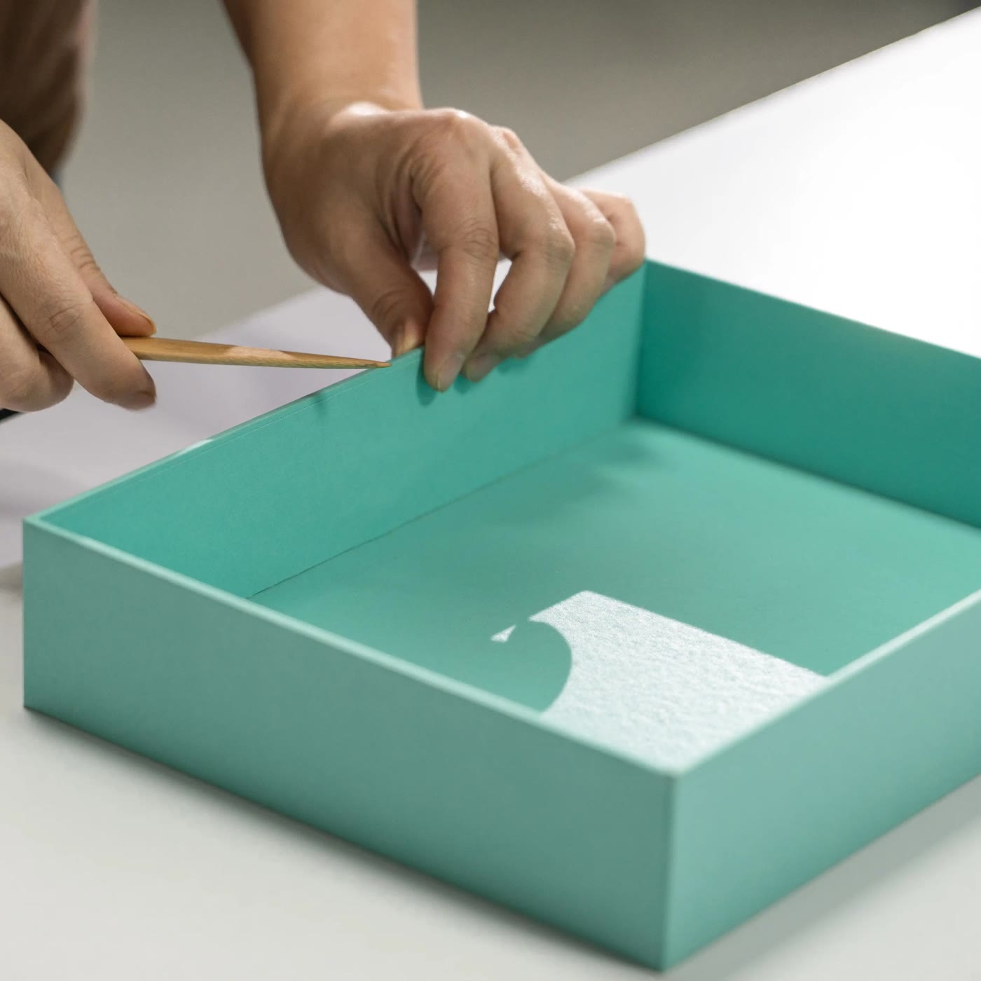 Macro detail of a hand-wrapped rigid box edge and lid