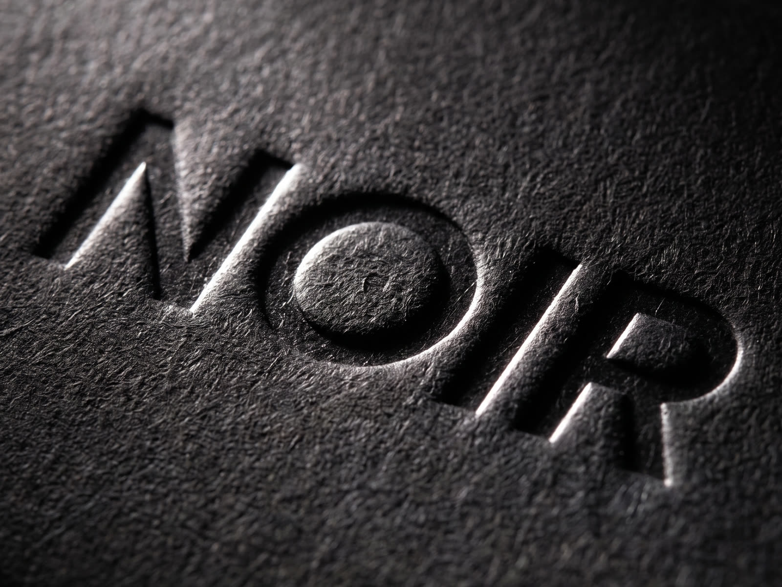 Macro of a debossed wordmark on matte black board