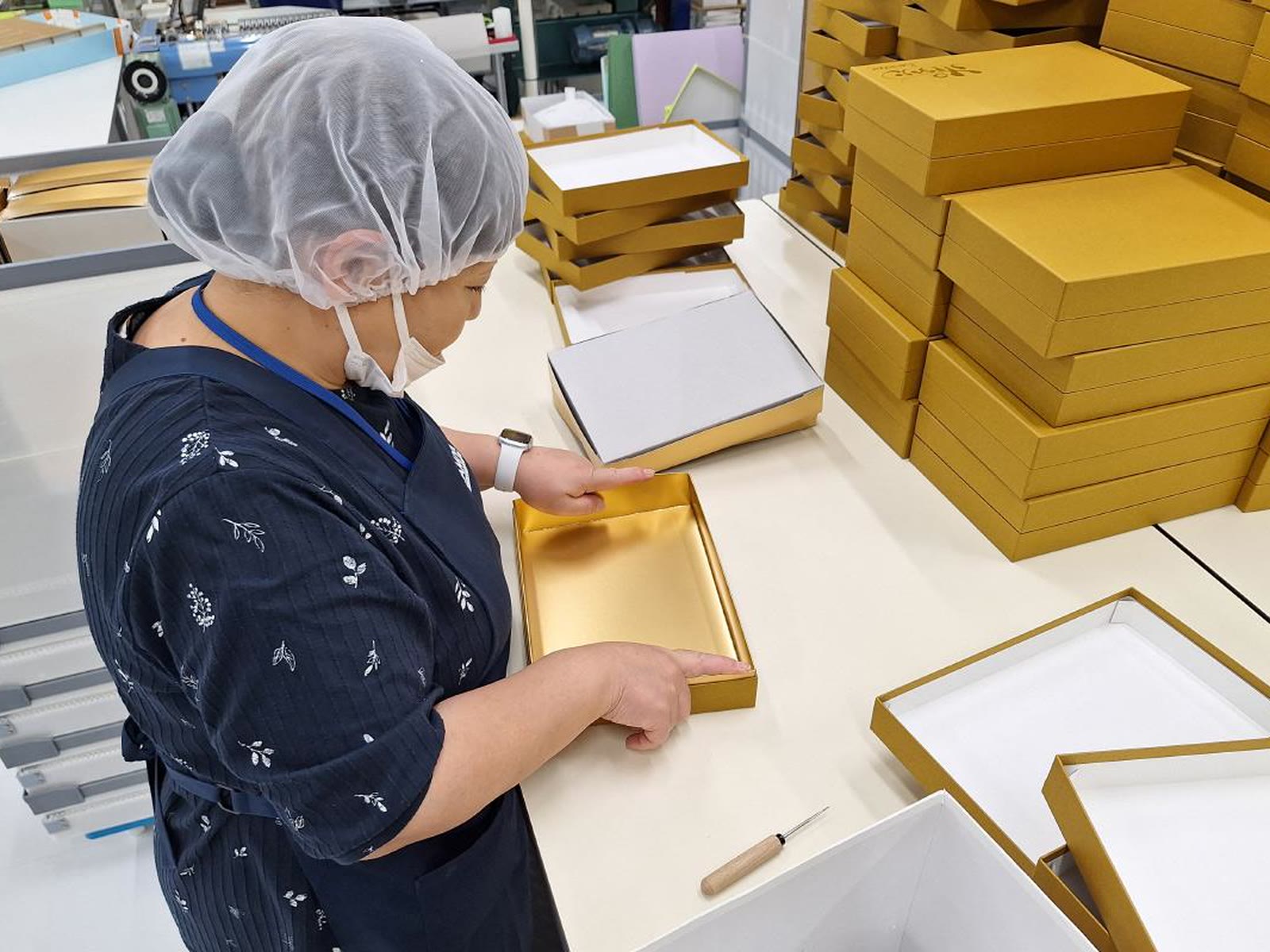 Gold rigid boxes being inspected before packing into a sample kit
